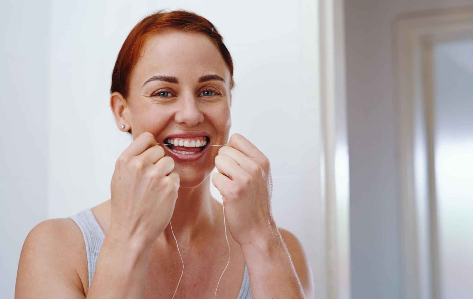 A woman flossing to help prevent future cavities.