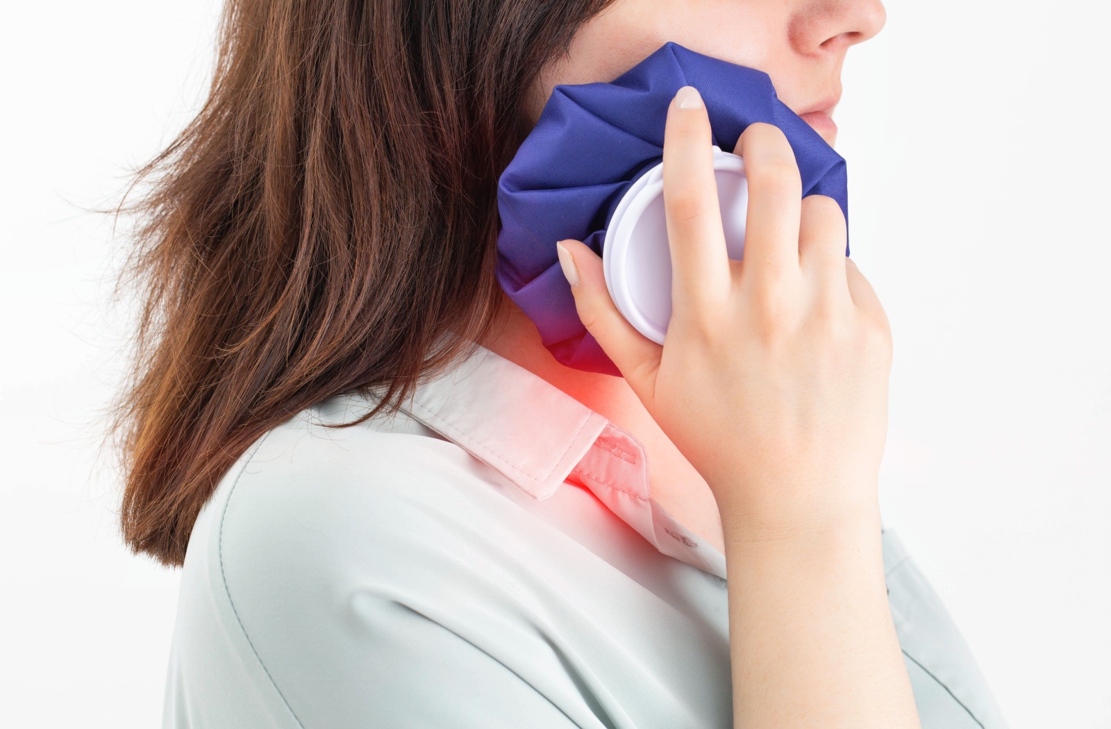 A dental patient holding a cold compress against their cheek after a tooth removal.
