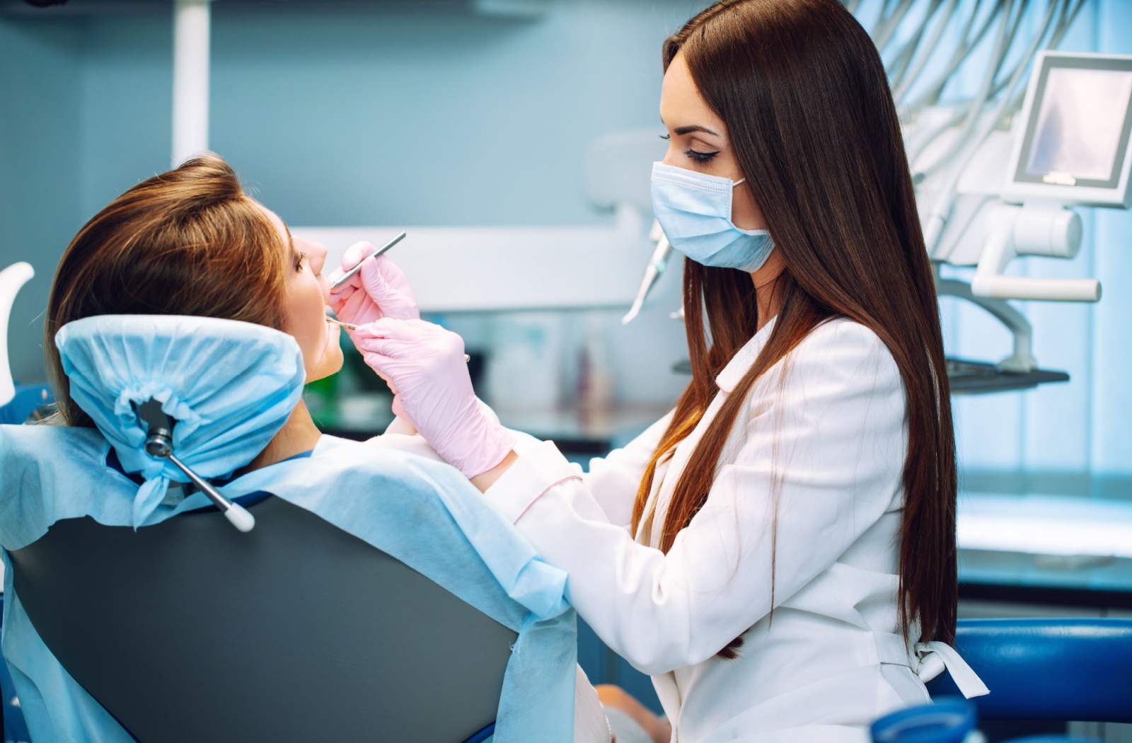 a dental hygienist looking at a person's mouth as they work on cleaning the patients teeth