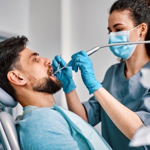 A dental hygienist cleans an adults teeth as part of their dentist appointment.