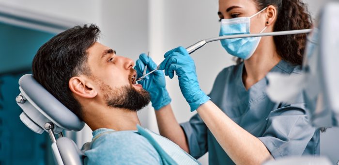 A dental hygienist cleans an adults teeth as part of their dentist appointment.