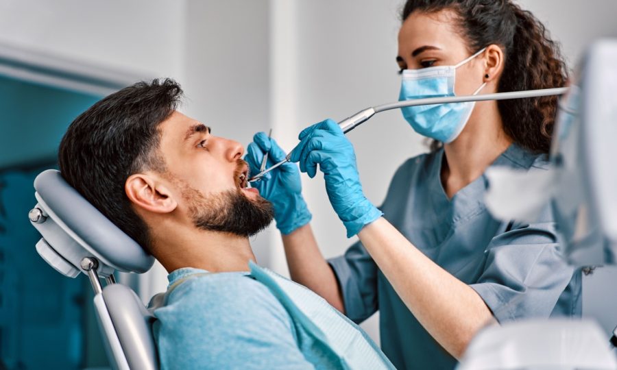 A dental hygienist cleans an adults teeth as part of their dentist appointment.