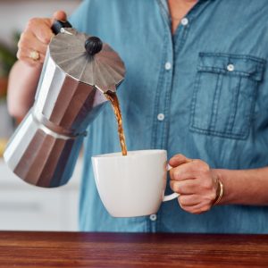 A close-up image of someone pouring a cup of coffee.