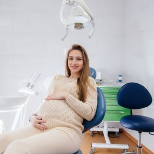 A pregnant woman sitting comfortably in a dental chair, smiling during her dental checkup.