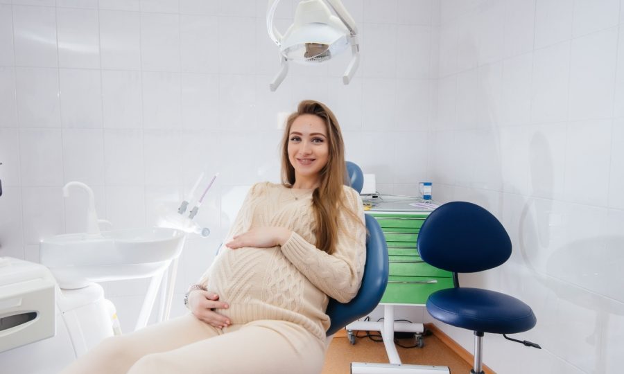 A pregnant woman sitting comfortably in a dental chair, smiling during her dental checkup.