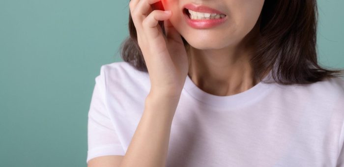 A woman holding her jaw due to tooth pain from a cavity.