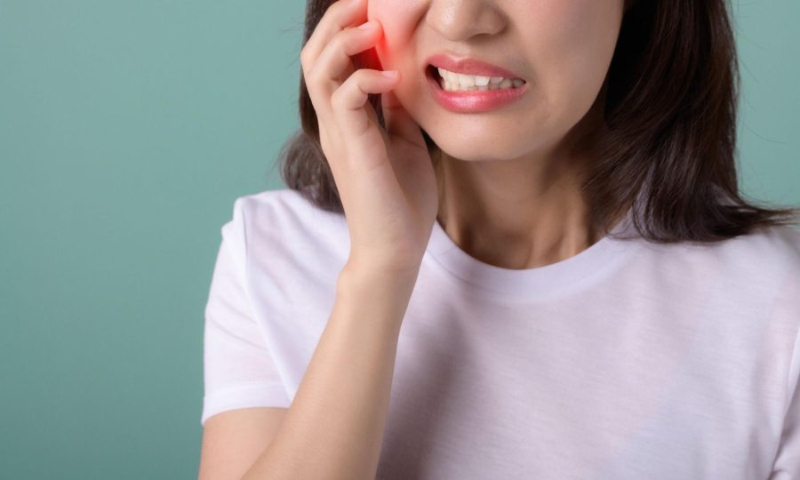 A woman holding her jaw due to tooth pain from a cavity.