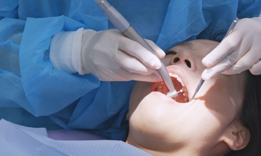 a person undergoing a dental cleaning done by a dental hygienist